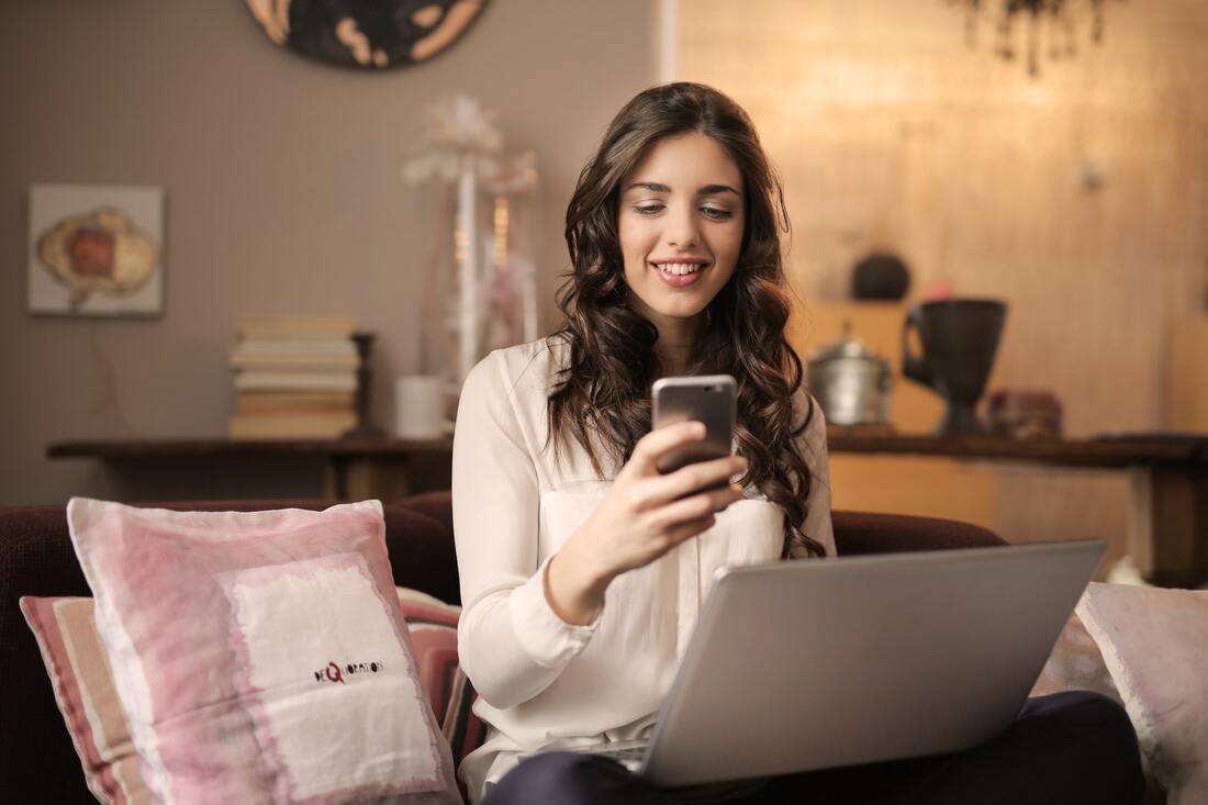 a woman holding a phone and a laptop